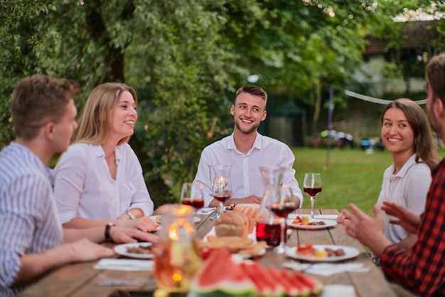 grupo de amigos felizes brindando com copo de vinho tinto enquanto fazia piquenique jantar francês ao ar livre durante as férias de verão perto do rio na bela natureza