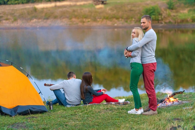 Grupo de amigos felizes com guitarra, se divertindo ao ar livre, perto da barraca da fogueira e do turista. Diversão de acampamento família feliz