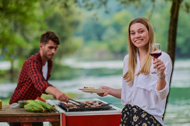 grupo de amigos felizes fazendo piquenique jantar francês ao ar livre durante as férias de verão perto do rio na bela natureza