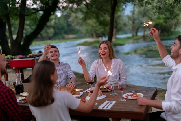 grupo de amigos felizes fazendo piquenique jantar francês ao ar livre durante as férias de verão perto do rio na bela natureza