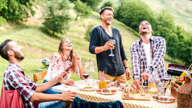 Grupo de amigos felizes se divertindo bebendo vinho tinto no churrasco pic nic garden party