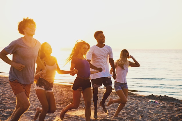 Grupo de amigos felizes se divertindo na praia ao amanhecer