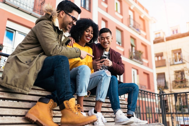 Grupo de amigos felizes usando o celular na rua. conceito de amizade.