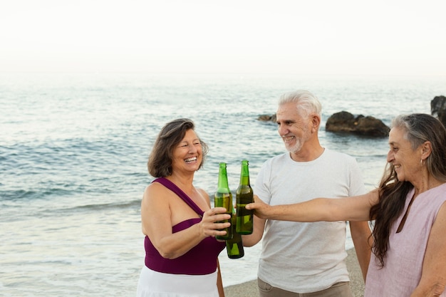 Grupo de amigos idosos torcendo com cerveja na praia