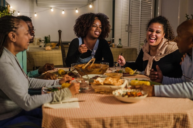 Grupo de amigos jantando juntos no terraço comemorando bons momentos juntos