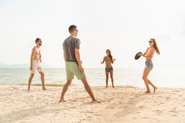 Grupo de amigos jogando disco deslizante na praia