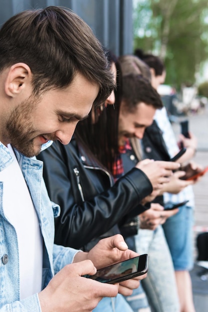 Grupo de amigos jovens e elegantes usando smartphones para mensagens em vez de comunicação real