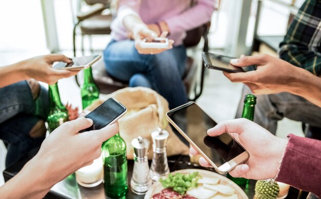 Grupo de amigos multiculturais se divertindo no smartphone em bar