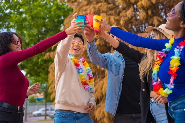 Grupo de amigos multiétnicos festejando em um parque Jovens diversos brindando com copos de cerveja em uma festa de verão Happy hour almoço e conceito de juventude