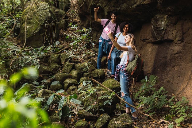 Grupo de amigos multirraciais curtindo a natureza durante uma caminhada - amigos sorrindo enquanto tiram uma selfie na selva.