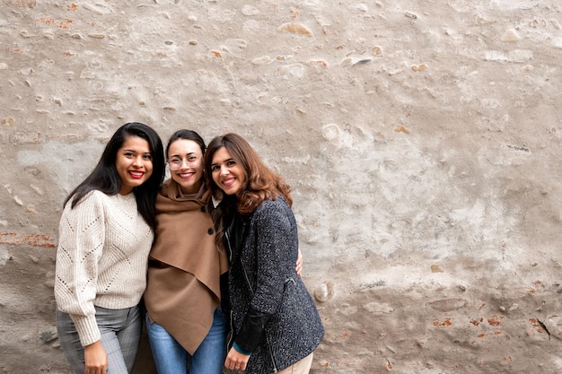 Grupo de amigos multirraciais do sexo feminino, olhando para a câmera. Mulheres felizes com a velha parede em plano de fundo e cópia de espaço.