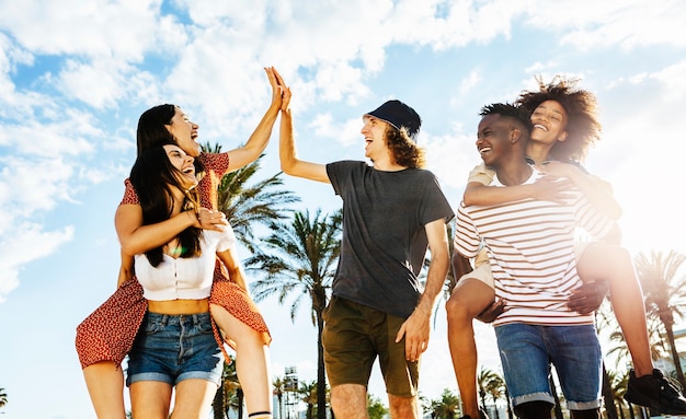 Grupo de amigos multirraciais felizes comemorando ao ar livre com luz do sol