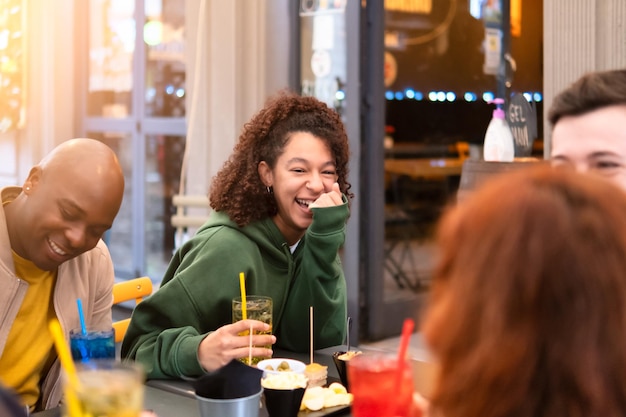 Grupo de amigos multirraciais felizes ri bebendo e comendo no restaurante conhecendo o conceito de estilo de vida