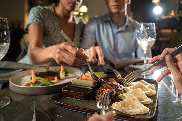 Grupo de amigos multirraciais se divertindo comendo no restaurante asiático, mas usando garfos restaurante europeu de cozinha asiática