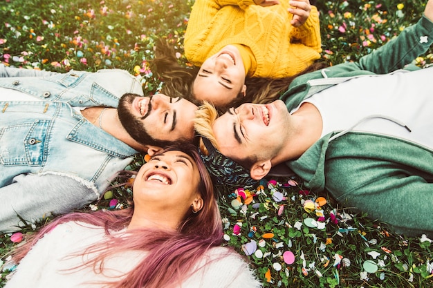 Grupo de amigos multirraciais se divertindo deitado na grama