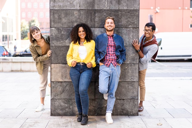 Grupo de amigos multirraciais se divertindo na parede do campus universitário Estudantes de cultura diversificada comemorando do lado de fora da cidade Jovens sorrindo olhando para a câmera para uma foto de grupo