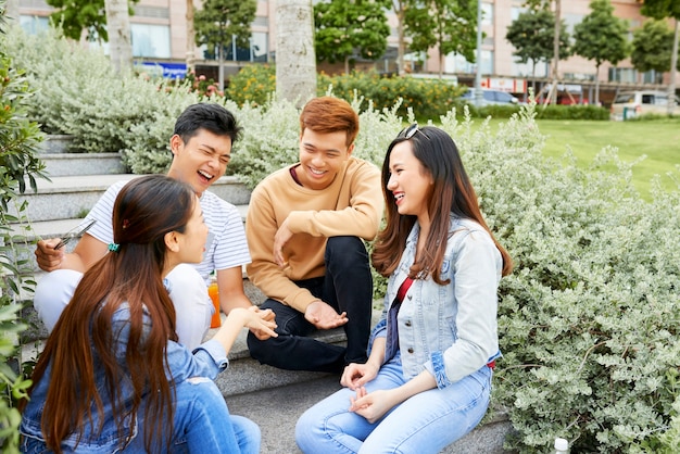 Grupo de amigos rindo e brincando enquanto descansava no parque da cidade em um lindo dia