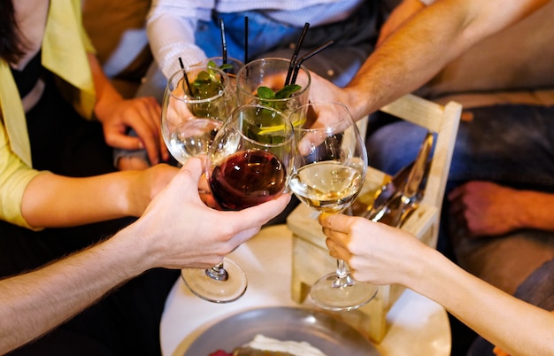 Grupo de amigos são copos clink com bebidas no café. Eles estão conversando e se divertindo