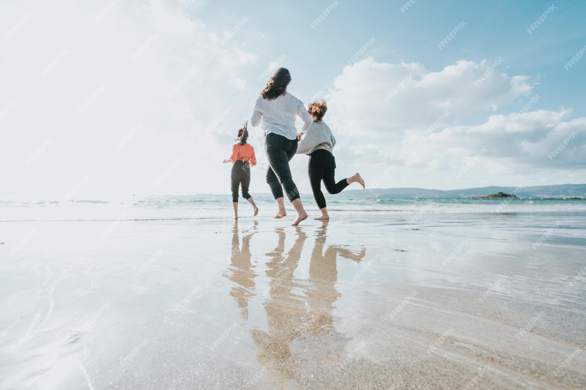 Grupo de amigos se divertindo, correndo juntos na praia de inverno.  multiétnico. todas as meninas do clube. três amigas rindo juntas - conceito  de amizade feminina. estilo de vida. fotografia freedom travel