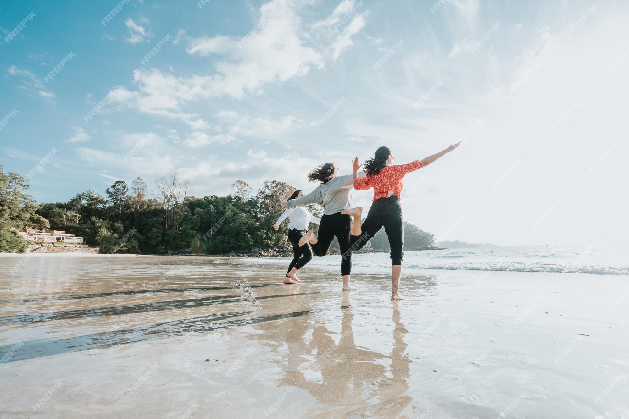 Grupo de amigos se divertindo, correndo juntos na praia de inverno.  multiétnico. todas as meninas do clube. três amigas rindo juntas - conceito  de amizade feminina. estilo de vida. fotografia freedom travel