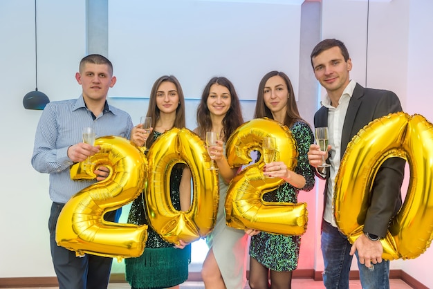 Grupo de amigos segurando balões de ar dourado 2020 em estúdio