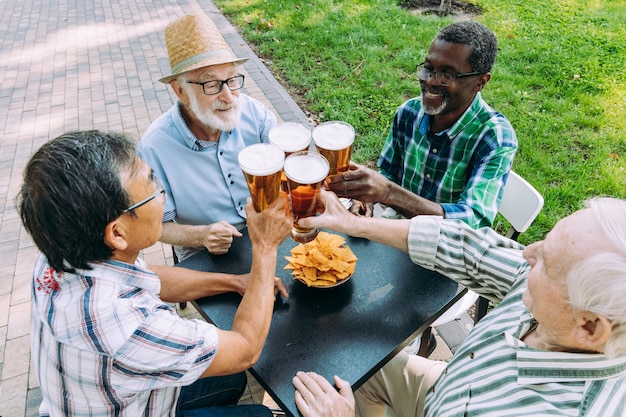 Grupo de amigos seniores bebendo uma cerveja no parque. Conceitos de estilo de vida sobre antiguidade e terceira idade