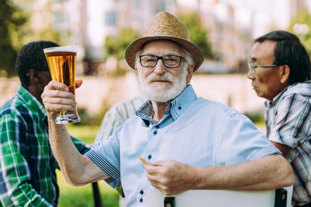 Foto grupo de amigos seniores bebendo uma cerveja no parque. conceitos de estilo de vida sobre antiguidade e terceira idade