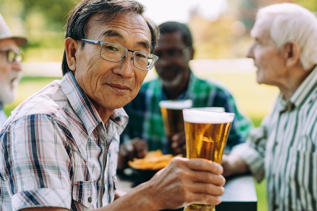 Grupo de amigos seniores bebendo uma cerveja no parque. Conceitos de estilo de vida sobre antiguidade e terceira idade