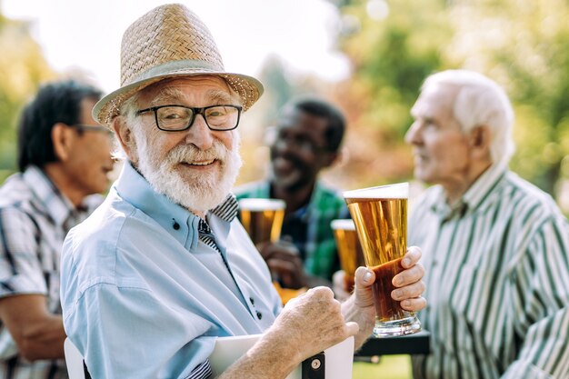 Grupo de amigos seniores bebendo uma cerveja no parque. Conceitos de estilo de vida sobre antiguidade e terceira idade