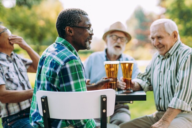 Grupo de amigos seniores bebendo uma cerveja no parque. Conceitos de estilo de vida sobre antiguidade e terceira idade