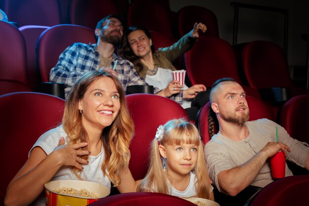 Grupo de amigos sentado na sala de cinema com pipoca e bebidas