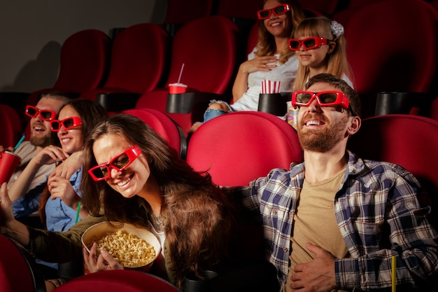 Grupo de amigos sentados no cinema com pipoca e bebidas