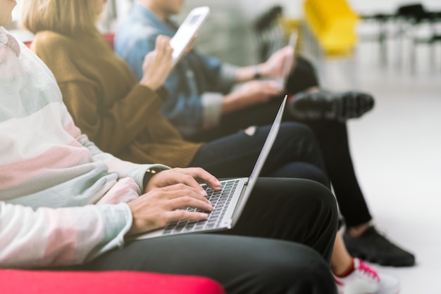 Grupo de amigos sentados no sofá usando a tecnologia de laptop e smartphone