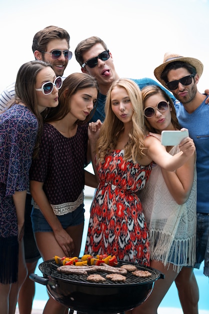 Grupo de amigos tomando uma selfie perto da piscina