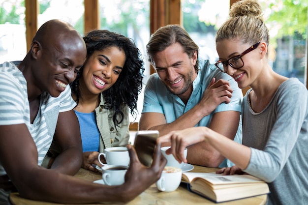 Grupo de amigos usando celular enquanto toma café