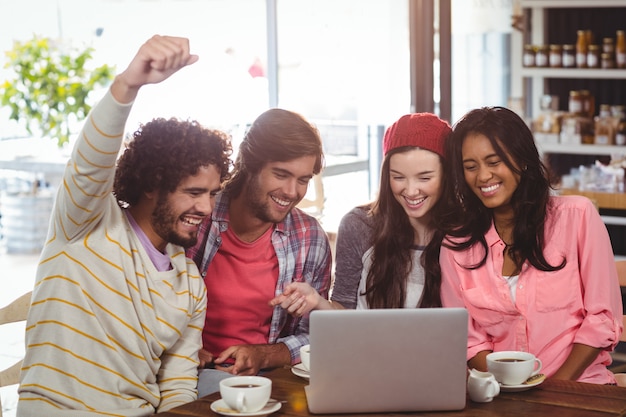 Grupo de amigos usando laptop enquanto tomar café