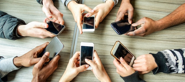 Grupo de amigos usando o smartphone. vista de mãos de pessoas se divertindo com telefones móveis