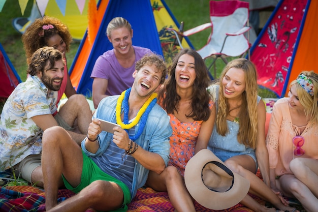 Grupo de amigos usando telefone celular no parque de campismo