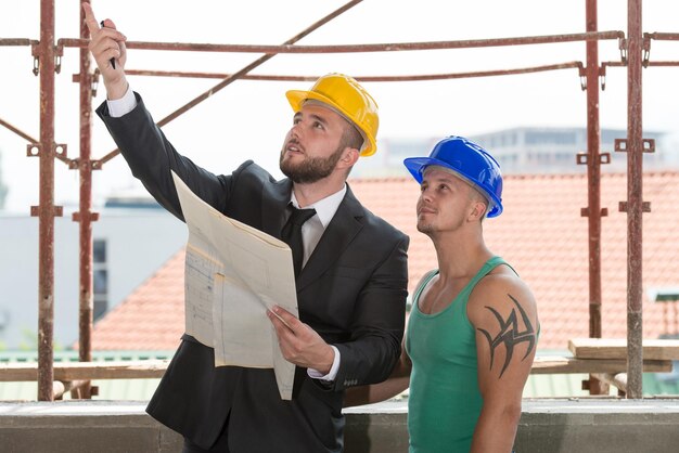 Grupo de arquiteto masculino e trabalhador da construção civil no canteiro de obras