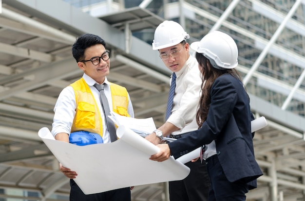 Foto grupo de arquitetos asiáticos discutindo sobre o novo projeto com papelada.