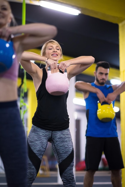 grupo de atletas jovens saudáveis, fazendo exercícios com kettlebells no cross fitness studio