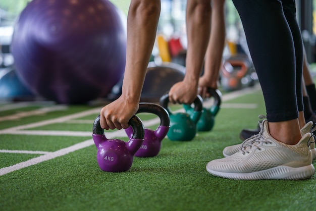 Grupo de Atlético jovem homem e mulher treino treino e exercício com peso kettlebell no clube de esporte fitness ginásio