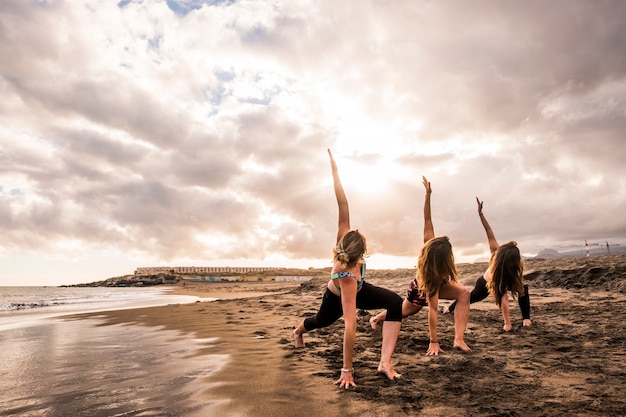 grupo de belas mulheres brancas fazendo exercícios de fitness na praia na costa