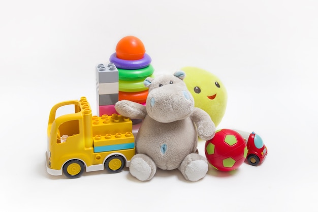 Grupo de brinquedos para crianças em um fundo branco. Construtor, pirâmide, bola e peluches para o desenvolvimento infantil