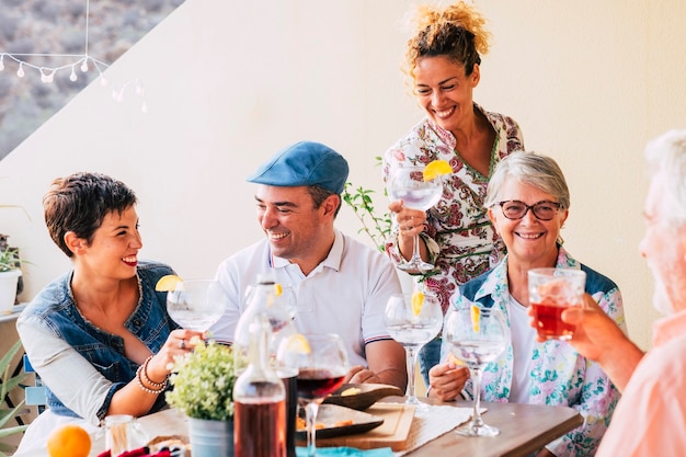 Grupo de caucasianos alegres e felizes juntos bebendo vinho e se divertindo na amizade