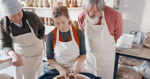 Grupo de cerâmica e professor moldam argila em estúdio ou oficina aprendendo com instrutora treinadora ou treinadora Lição de arte e as pessoas praticam artes de passatempo ou elaboram copos ou tigelas de caneca de cerâmica feitos à mão