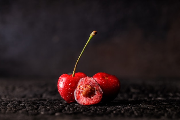 Grupo de cereja em uma mesa de madeira escura. frutas suculentas cereja frescas. close de um grupo de frutas