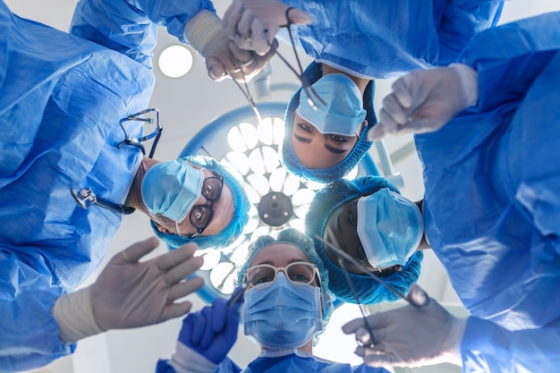 Grupo de cirurgiões na sala de cirurgia com equipamento cirúrgico