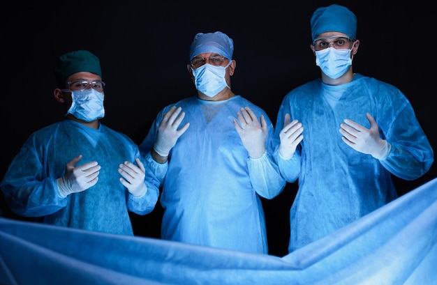 Grupo de cirurgiões no trabalho em sala de cirurgia em tons de azul. Equipe médica realizando operação