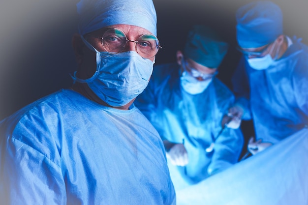 Grupo de cirurgiões trabalhando na sala de cirurgia em tons de azul Equipe médica realizando operação